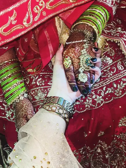 A heartfelt moment between friends, showing the beautiful dark stain of the bride's henna.