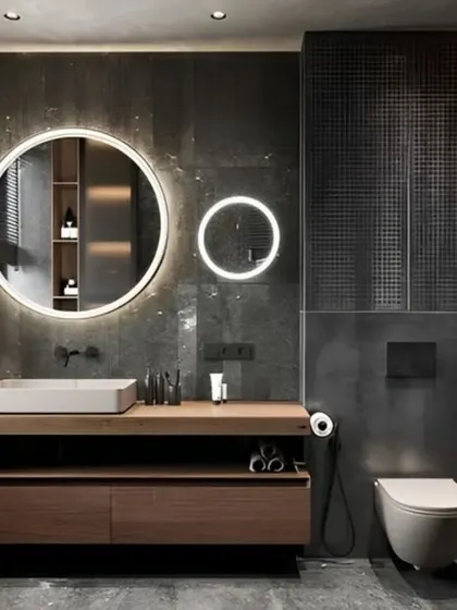 A dark and moody bathroom design featuring large-format gray tiles and a floating wood vanity. The dual backlit mirrors provide ample, flattering light, enhancing the room's modern and luxurious feel.