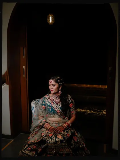 A solo portrait of the bride seated in a doorway, framed with a vintage film effect.