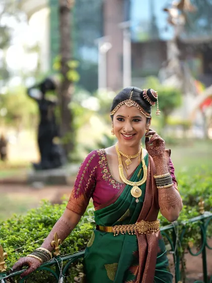The complete look, with the unique hairstyle featuring a side bun and traditional hair jewelry, perfectly complementing her Brahmin wedding attire.