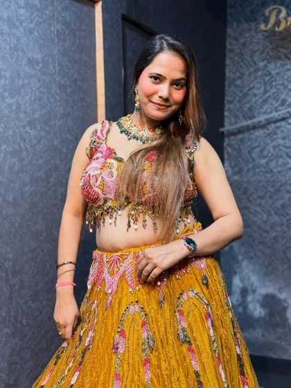 A close-up of the vibrant yellow haldi lehenga, showing the colorful embroidery on the blouse.