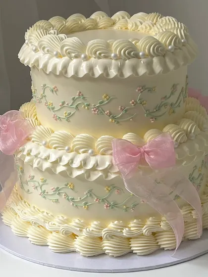 A beautiful two-tiered vintage cake with delicate, hand-piped buttercream details and soft ribbon bows. This style is perfect for elegant celebrations and is a key part of our buttercream skills curriculum.