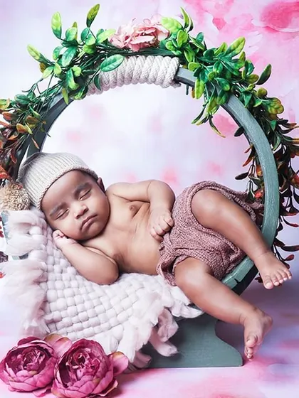 An adorable shot of an awake baby relaxing in a round floral hoop prop. This pose is great for babies who are calm and observant.