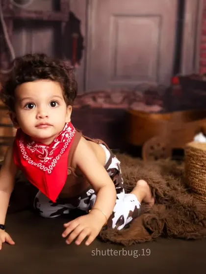 A curious little cowboy crawling through our rustic ranch setup, complete with a red bandana and cow-print pants.
