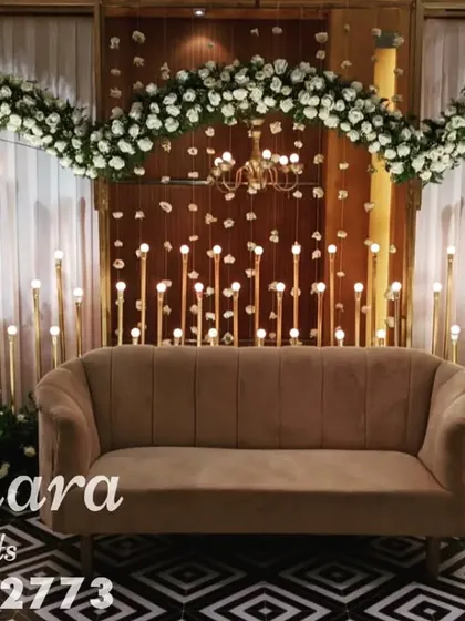 This modern reception stage combines white floral arches with dramatic chandeliers and candle stands. The geometric black and white flooring adds a contemporary edge to the overall design.