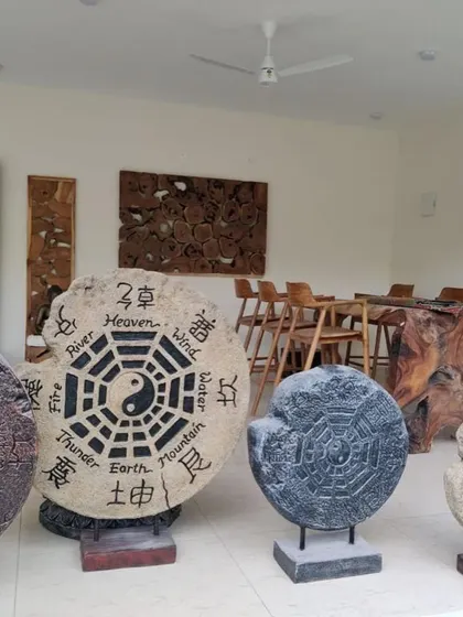 A collection of Bali-style sculptures, including Yin and Yang stone discs and other wooden art pieces.