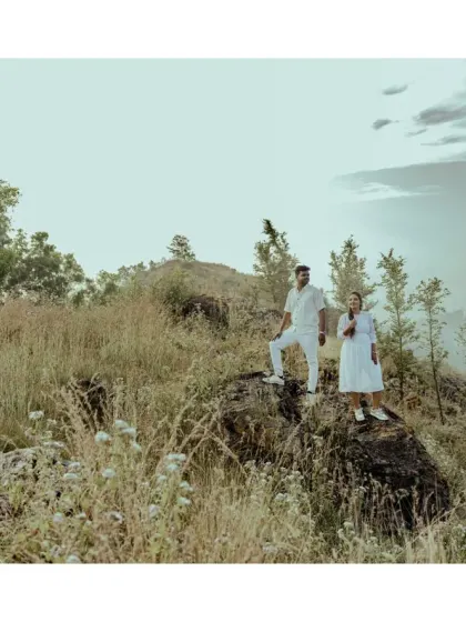 A couple stands on a rocky outcrop overlooking a vast landscape. This shot captures a sense of adventure and looking towards the future together.