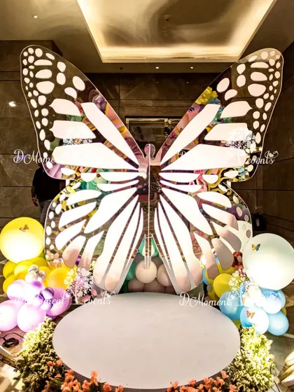 A spectacular butterfly-shaped stage provides a unique and dramatic backdrop for photos and cake cutting at a wonderland-themed party.