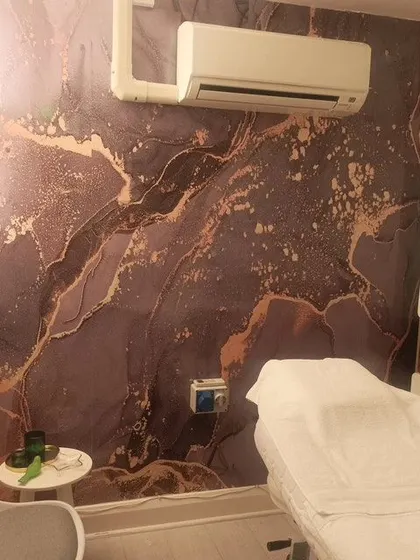 Here is a finished installation of a dark marble wallpaper with rose gold accents in a spa room. The luxurious texture and color palette create a deeply relaxing and high-end atmosphere for clients.