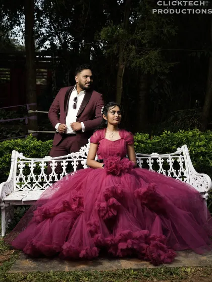 A fairy-tale moment in a garden, with the bride in a magnificent ruffled gown sitting on a bench next to her groom.