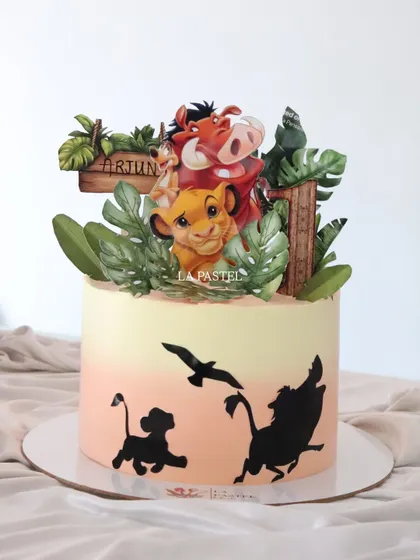 Another view of the Hakuna Matata cake, showing the personalized name sign and the lush jungle foliage surrounding the characters.