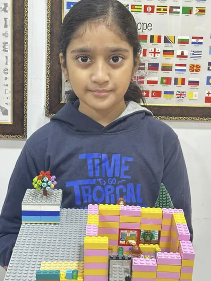 This student built a multi-level house with a small garden, demonstrating her ability to plan and execute a detailed LEGO project.