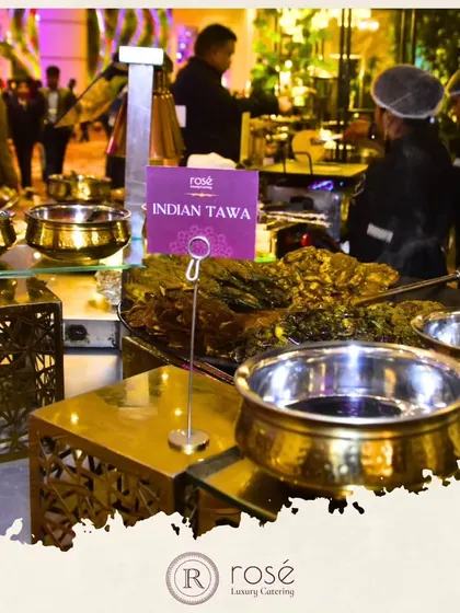 An "Indian Tawa" live station in full swing at an evening event. The combination of our signature brass serveware and the dynamic cooking process creates a warm and inviting atmosphere.