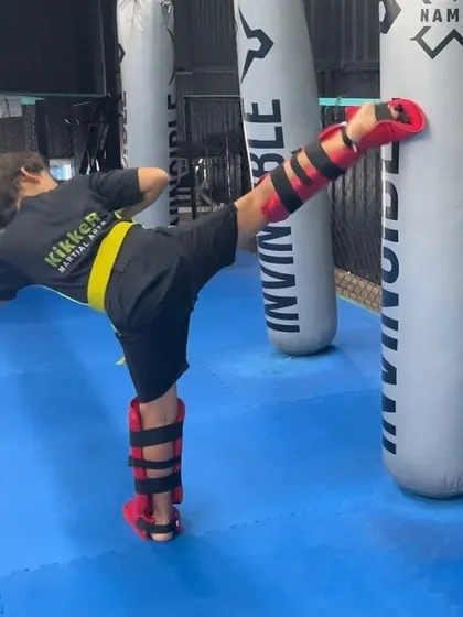 Reaching new heights with every kick. A young student practices on the heavy bag, building power and perfecting his form.