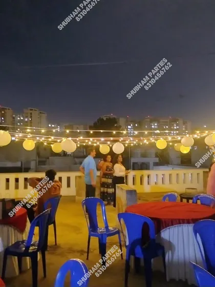 A simple and elegant rooftop party setup with string lights and paper lanterns.