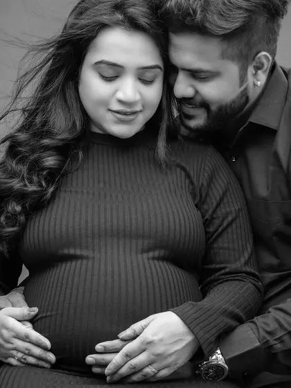 An intimate black and white close-up of a couple cradling the baby bump. This pose focuses on the hands and the connection between the parents and their unborn child.