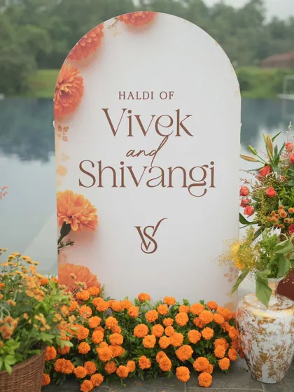 A personalized welcome sign for Vivek and Shivangi's Haldi, set against a poolside backdrop and surrounded by marigolds.