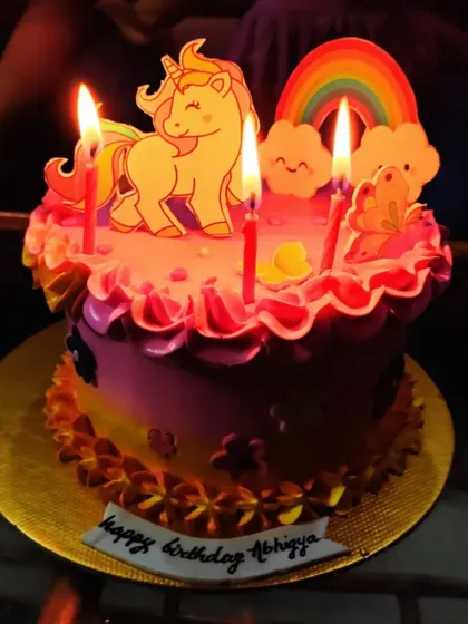 The birthday girl's unicorn cake lit up with candles, ready for a wish to be made.