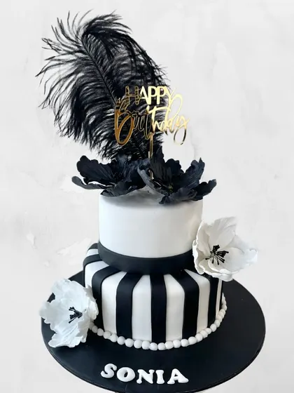 A chic black and white cake for Sonia's birthday. The design features bold stripes, elegant sugar flowers, and a dramatic black feather for a touch of Great Gatsby glamour.