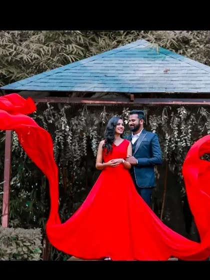 A couple poses in a garden gazebo, framed by the long, flowing trails of our red flying dress.