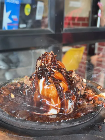 A close-up of the Sizzling Brownie, covered in molten chocolate sauce and topped with ice cream.
