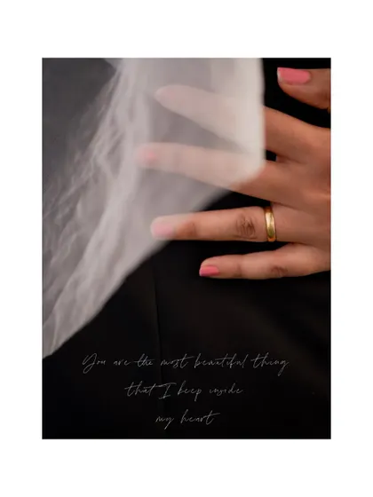 A close-up, artistic shot of the bride's hand with her wedding ring, resting on the groom's suit, with a romantic quote.