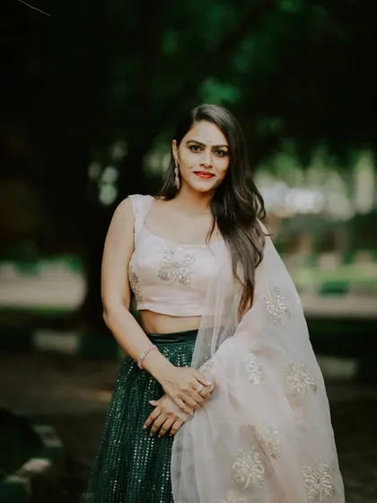 A close-up portrait of the model in the green and pink lehenga. This rental piece is perfect for guests attending a wedding or a reception.