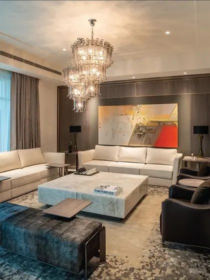 A spacious and open living room where comfort is key. The furniture arrangement includes multiple sofas and armchairs in neutral tones, creating an inviting atmosphere for large gatherings. The design emphasizes clean lines and high-quality materials to achieve a look of timeless elegance.