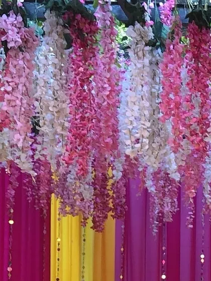 A beautiful detail shot of hanging floral decor. We used strings of artificial wisteria in shades of pink and white against a colorful draped background to create a dreamy, layered effect.