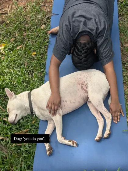 Even our four-legged friends know the importance of a good stretch. A student in Balasana (Child's Pose) gets a gentle reminder to relax from our furry companion.
