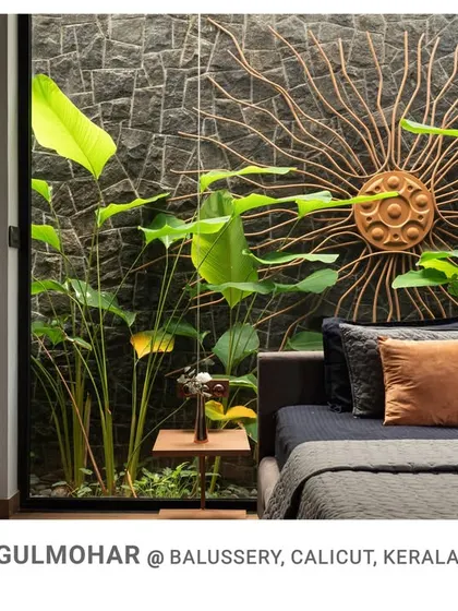 A close-up of the Gulmohar bedroom's connection to its private courtyard, where a custom sun-shaped metal art piece is mounted on the exterior stone wall.