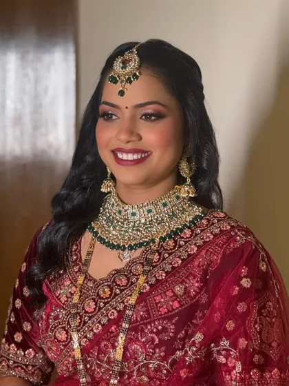 A bride fit for royalty. This look features a beautiful smile, glowing skin, and shimmery eye makeup that perfectly complements her heavy kundan jewelry.