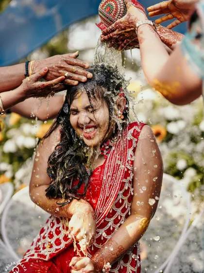 A dynamic shot of the bride getting drenched with water during a fun Haldi ritual.