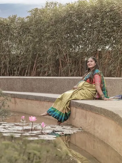 A peaceful moment by a lily pond, with the mom-to-be dipping her toes in the water, dressed in a lovely traditional saree.