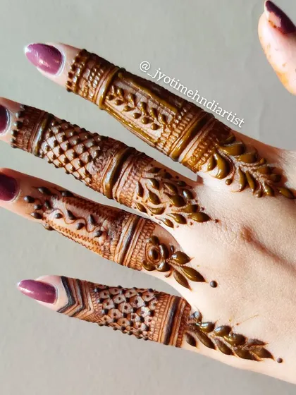 A close-up of detailed finger henna, showing a variety of patterns and techniques on each finger.