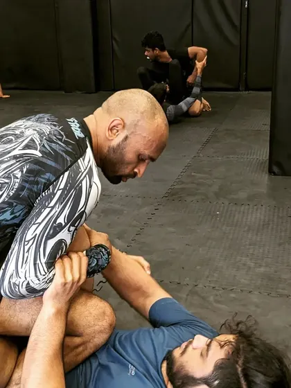 A BJJ grappling exchange on the mat. Here, a fighter works to pass the guard, a fundamental skill in Brazilian Jiu-Jitsu that we teach to all our students.