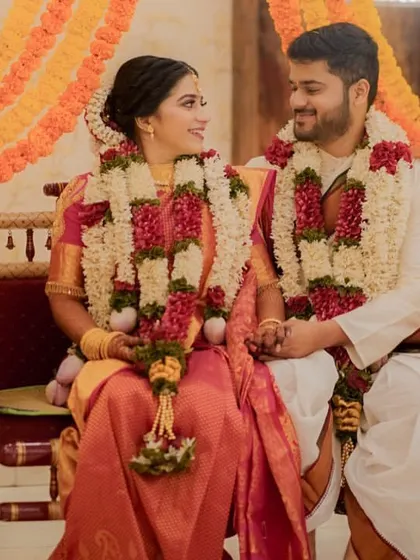 The couple seated on a traditional swing decorated with marigolds, sharing a sweet look during their South Indian wedding ceremony.