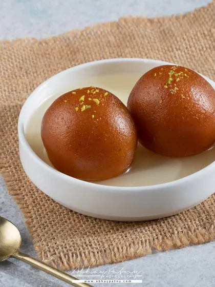 A simple, elegant shot of Gulab Jamun. The focus is entirely on the perfectly round, syrup-soaked sweets, with a clean composition that makes them look incredibly tempting.