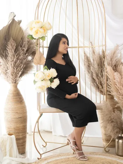 A serene portrait of a mom-to-be seated in our golden birdcage chair. The black dress against the light and airy boho props creates a beautiful contrast.