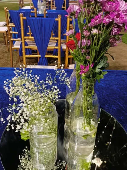 A simple and creative centerpiece using recycled bottles, baby's breath, and purple flowers, adding a sustainable touch to the decor.