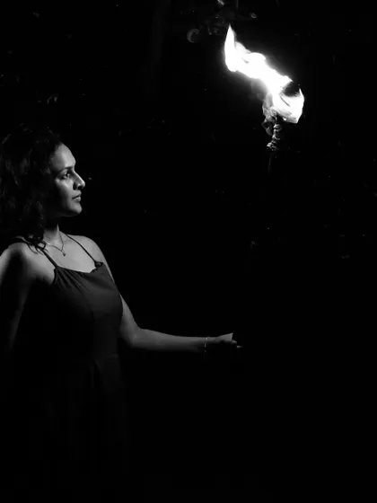 A beautiful black and white solo portrait of the bride-to-be, looking thoughtfully at a flame she appears to be holding. This artistic shot uses light and shadow to create a magical and contemplative mood.