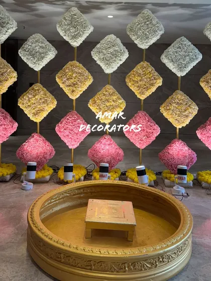 A minimalist Haldi setup can still make a big impact. Here, I used a modern backdrop of textured floral squares in pink, yellow, and white, with a traditional golden 'urli' in the center for the ceremony.