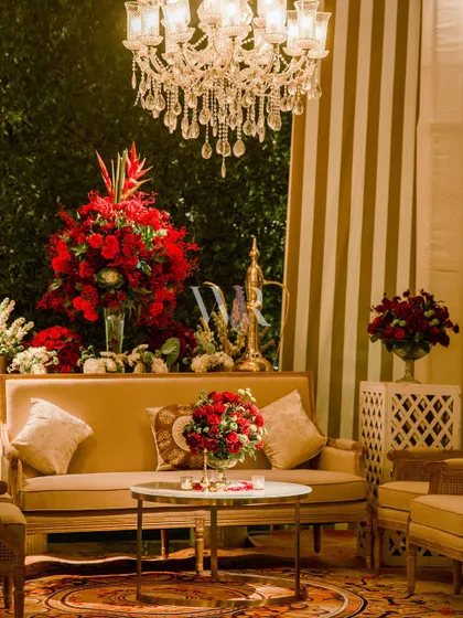 A comfortable seating nook within the lounge area. The combination of the striped backdrop, a plush sofa, and a large red floral arrangement creates a stylish and inviting corner.