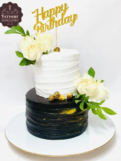 A chic black and white two-tier birthday cake. The contrasting colors and clean lines, accented with fresh white roses, create a modern and sophisticated look suitable for any elegant celebration.