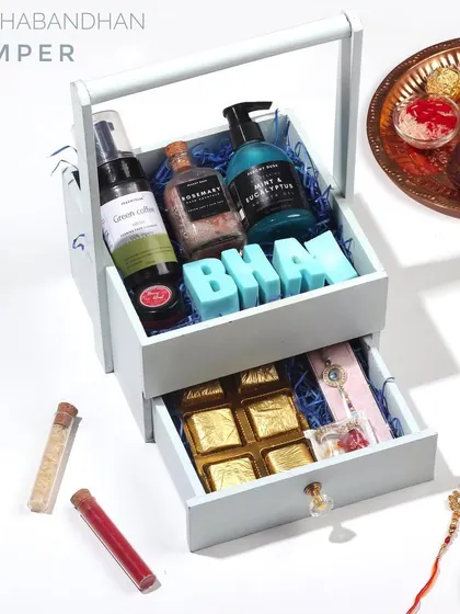 Elevate the joy of Raksha Bandhan with this stunning hamper in a two-drawer wooden basket. It's overflowing with organic skincare, a traditional rakhi, and delightful handmade chocolates.