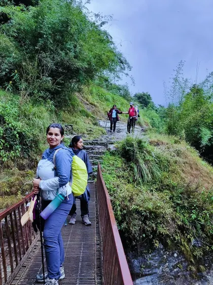 A trekker crosses a small bridge on the Annapurna trail. The journey is filled with varied terrain, from lush forests and terraced farms to high mountain passes.