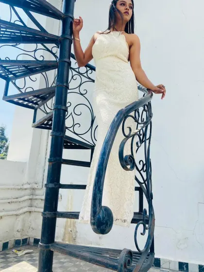 A dramatic pose on a spiral staircase, highlighting the sophisticated design of this rental gown.