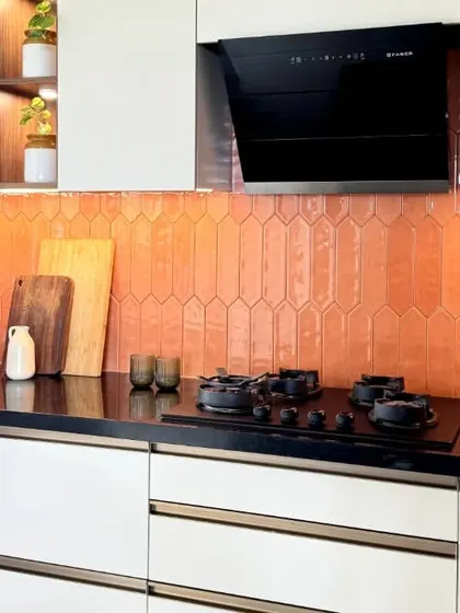 A close-up of the orange picket tile backsplash, which adds a pop of color and texture to this otherwise neutral kitchen. The design proves that functional spaces can also be fun.