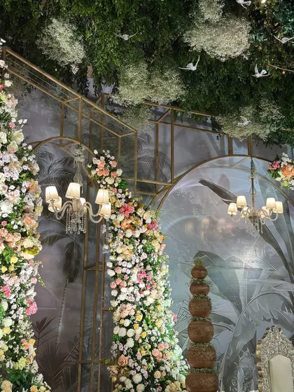 A beautiful composition of cascading floral pillars, classic chandeliers, and a tropical-themed backdrop. The layers of decor create a rich and immersive experience.
