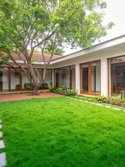 The courtyard is designed with a lush lawn and stone pathways, serving as a multi-functional space for relaxation, gatherings, and safe play for children.